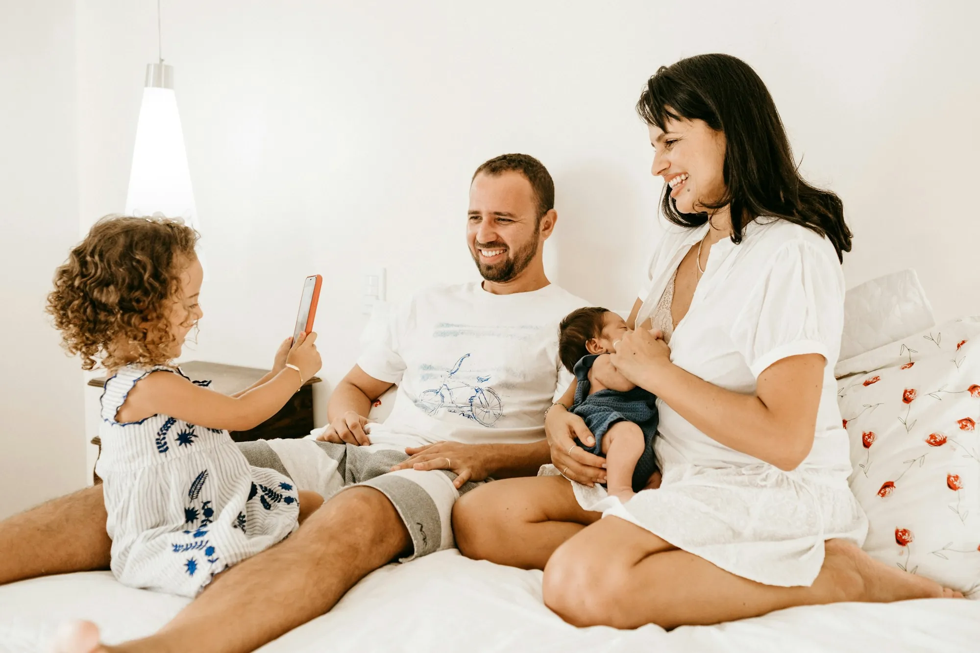 Parents relaxing on a bed with their toddler and baby